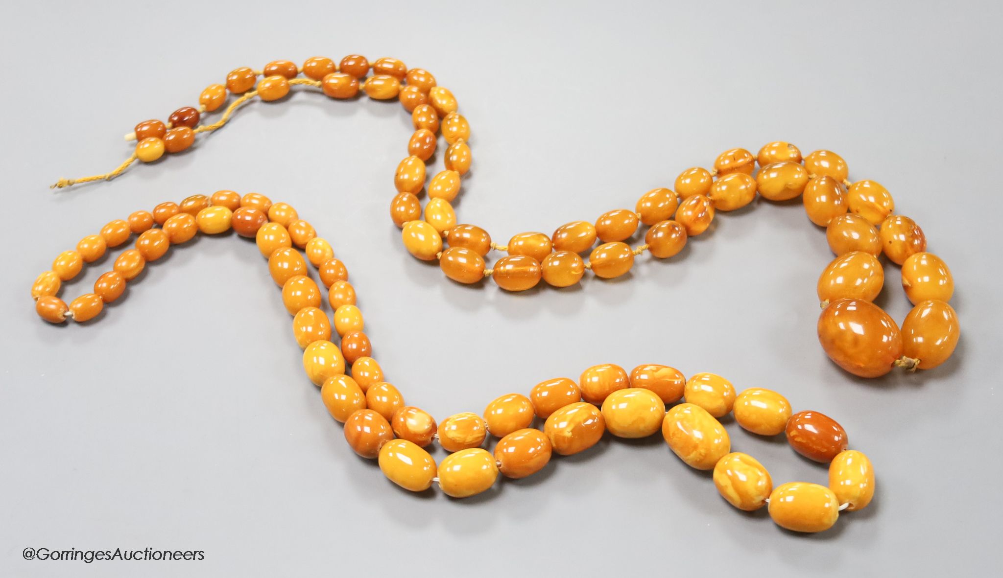 Two single strand graduated oval amber bead necklaces, 71cm, 61 grams & 89cm, 68 grams (beads missing from larger necklace)